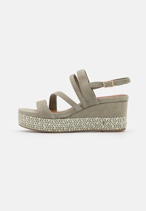 Sandale compensée avec trois brides en daim, une bride de cheville avec boucle et une semelle plateforme tressée de couleur vert olive clair.
