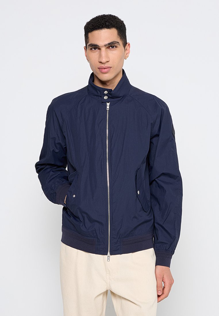 Navyblaue Zip-Jacke mit hohem Kragen, Seitentaschen, gerippten Bündchen und Saum, aus leichtem Material mit glatter Textur.