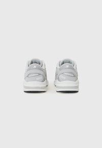 Grå New Balance 1000 sneakers med en texturerad mesh-ovandel, vadderad mellansula och framträdande logotyp på hälen.