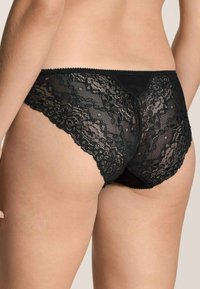 Schwarze Spitzenunterwäsche mit floralem Muster, ausgestattet mit einem weichen Bund und gewellten Kanten. Semi-transparenter Rücken mit glattem schwarzen Stofffutter.