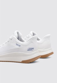 Białe buty sportowe z teksturowaną cholewką z siateczki, smukłym designem, wyściełanym kołnierzem i gumową podeszwą. Posiadają niebieski detal z logo po boku.