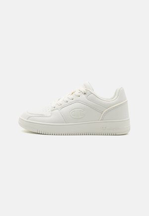 Weiße Sneakers aus synthetischem Leder, mit perforiertem Zehenbereich, Schnürdesign und einem Logo an der Seite. Flache Gummisohle.