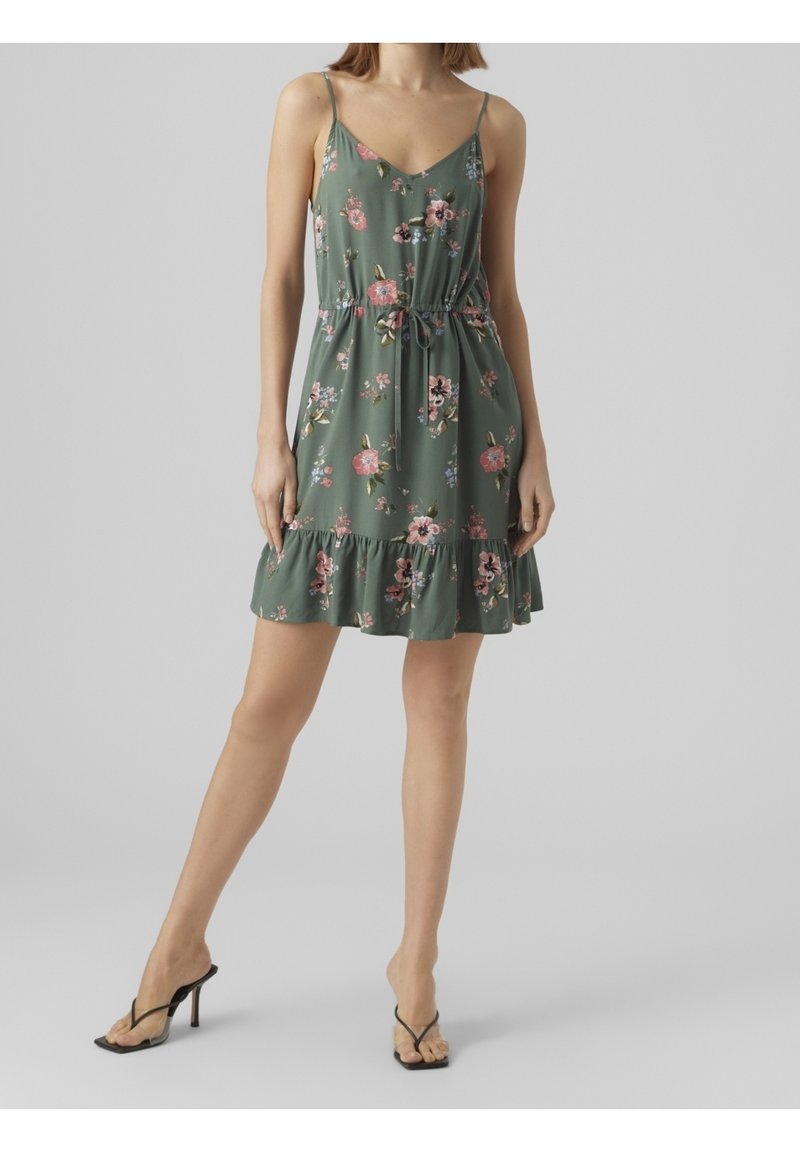 Šaty s květinovým potiskem ze zelené látky, s tenkými ramínky, nařaseným pasem a volánkovým lemem. Výrazné vzory růžových a černých květin.