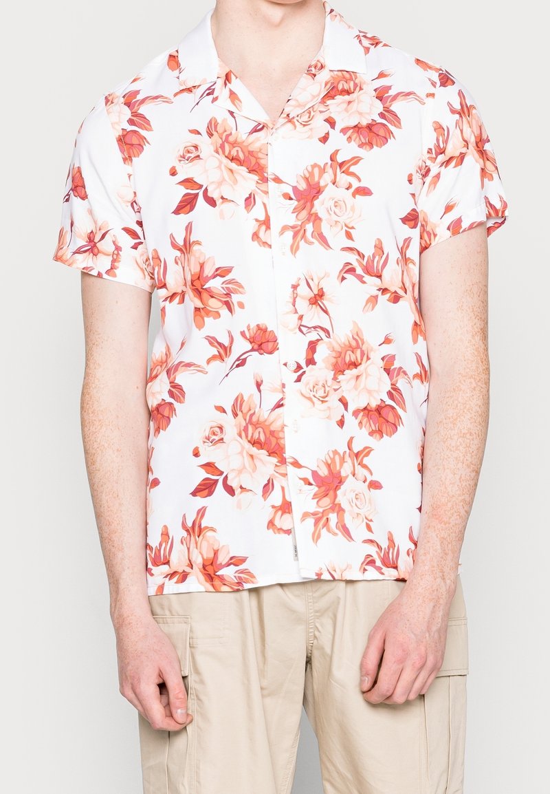 Camicia a maniche corte con una base bianca decorata da grandi motivi floreali nei toni del corallo e pesca. Chiusura con bottoni sul davanti e colletto.