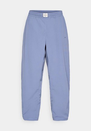 Vaaleansiniset Nike-housut, jotka on valmistettu pehmeästä, kevyestä kankaasta. Niissä on joustava vyötärönauha ja sivussa minimaalinen brändäys.