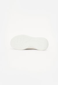 Semelle de chaussure avec un design texturé ; matériau en caoutchouc blanc avec une semelle à motif pour adhérence et stabilité.