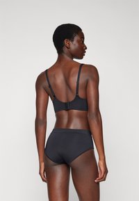 Black bra and matching high-waisted underwear made of smooth fabric. Adjustable straps, minimal seams, and hooks at the back for support.