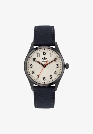 Schwarz Uhr mit beigem Ziffernblatt, navyblauem Textilarmband, arabischen Ziffern und rotem Sekundenzeiger. Adidas-Logo auf dem Ziffernblatt.