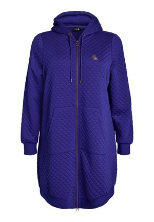 Lilla lang quiltet hættetrøje med lynlås foran, snor til hætten, to forlommer, ribbede manchetter og et lille logo på brystet.