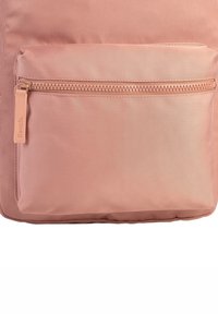 Sac à dos en tissu rose avec une poche avant zippée à finition texturée et un zip de marque portant la mention "Bench."