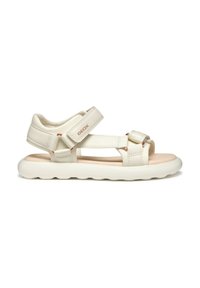 Sandali bianchi in eco-pelle con cinturini regolabili in velcro, soletta imbottita beige e suola in gomma testurizzata con un motivo ondulato.