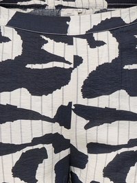 Gros plan sur un tissu à motifs abstraits noir et blanc avec de fines rayures verticales et une ceinture froncée.