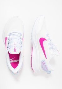 Scarpe da corsa bianche con tessuto in rete, baffo Nike rosa e dettagli. Lacci in blu chiaro e fodera interna rosa con il testo "RUNNING".