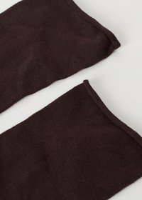 To stykker mørkebrunt stof, der viser et glat, struktureret strikmateriale med rå kanter, placeret på en lys farvet overflade.