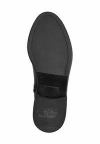 Sole di scarpa nera con un design in gomma testurizzata, con una sezione in pelle liscia e logo del marchio impresso. Forma piatta con una leggera curvatura.