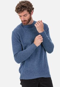 Pull en tricot bleu clair avec un col rond, des manches longues, et des poignets et un ourlet côtelés. Texture douce avec un motif chiné subtil.