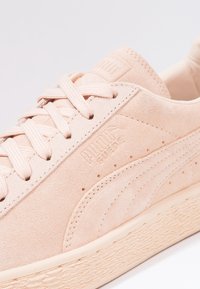 Puma mockasins i mjuk rosa, med en texturerad ovandel, runda skosnören och en texturerad gummisula med en diskret prägling av varumärket.