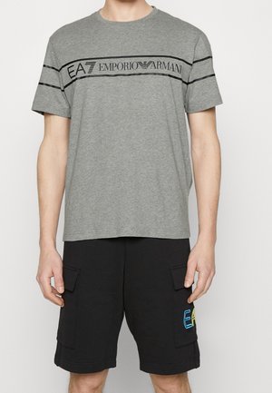 Homme portant un t-shirt gris EA7 Emporio Armani et un short cargo noir avec des rabats de poche et un logo EA7 coloré.