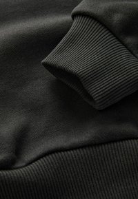 Mörkgrå sweatshirttyg med ribbad mudd och subtil struktur, som visar mjukt, slätt material med en strukturerad design.