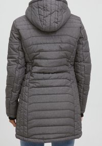 Grå vadderad jacka med huva, med horisontellt quiltat mönster, fickor med dragkedjor och kontrasterande ribbade muddarna.