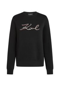 Sweatshirt noir à manches longues avec un col rond, présentant le mot "Karl" en texte cursif pailleté sur la poitrine.