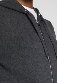 Donkergrijze zip-up hoodie met een gestructureerde stof, een capuchon met trekkoord, een zilveren rits en voorkruiden.