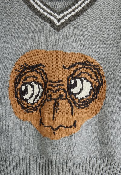 Γκρίζα ζακέτα με πλέκτο σχέδιο προσώπου χαρακτήρα με μεγάλα μάτια, περιγραμμένα σε μαύρο χρώμα, και καφέ, υφασμάτινη λεπτομέρεια. Σχέδιο V-λαιμού με ριγέ λεπτομέρειες.