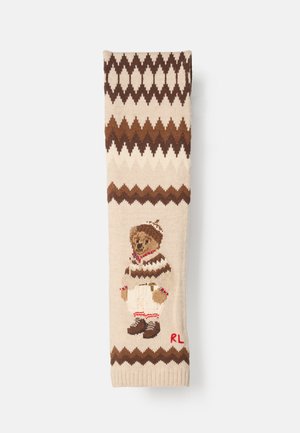 Sweater de malha com base em tons de bege e padrões zigzag castanhos. Urso de peluche bordado com um suéter segura um sino, com "RL" vermelho na parte inferior.