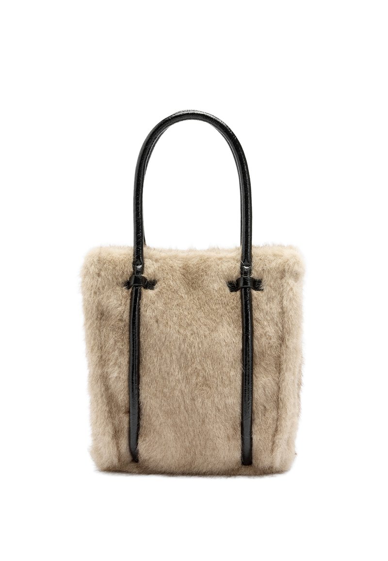 Beżowa torba typu tote z futerkiem z materiału syntetycznego, z połyskującymi czarnymi skórzanymi uchwytami, w kształcie prostokąta i z przeszyciami na górze. Miękka tekstura.