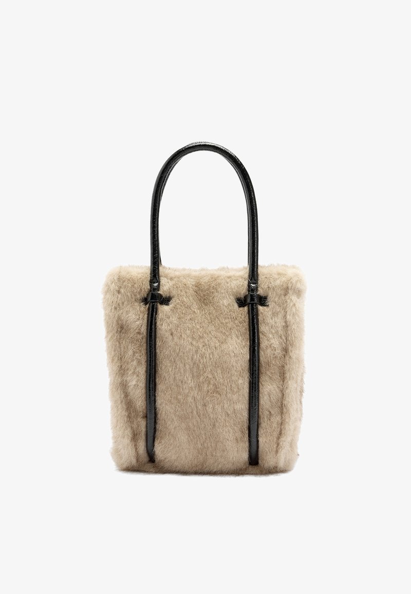 Beżowa torba typu tote z futerkiem z materiału syntetycznego, z połyskującymi czarnymi skórzanymi uchwytami, w kształcie prostokąta i z przeszyciami na górze. Miękka tekstura.