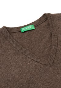 Maglione marrone a scollo a V realizzato in tessuto morbido. Collo e orlo a costine, con un'etichetta verde che riporta il logo "United Colors of Benetton".