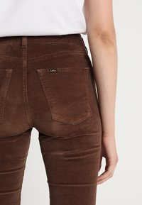 Bruna kordbyxorna med slim fit har två bakfickor, sydda detaljer och en liten logotyp på höger ficka.