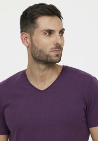 V-hals, kortebloes t-shirt in donkerpaars katoen met een discreet reliëf logo op de borst, gladde textuur en casual pasvorm.