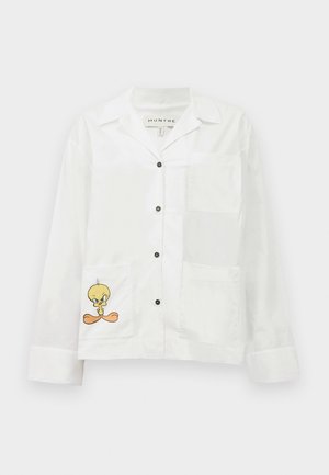 Chemise blanche à boutons avec une poche poitrine et deux poches avant. Dotée d'un oiseau cartoon imprimé sur la poche inférieure. Texture lisse.