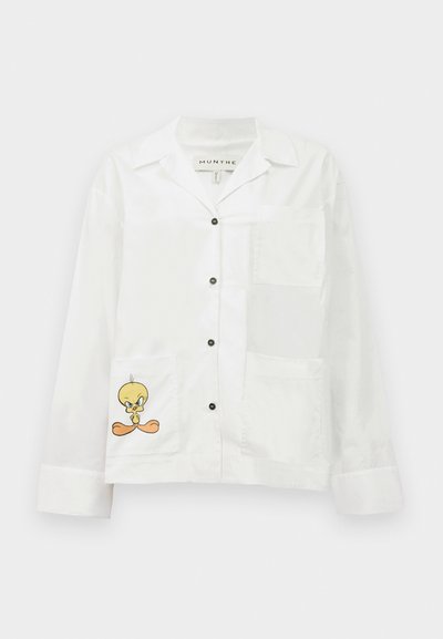 White button-up shirt with a chest pocket and two front pockets. Features a printed cartoon bird on the lower pocket. Smooth texture.