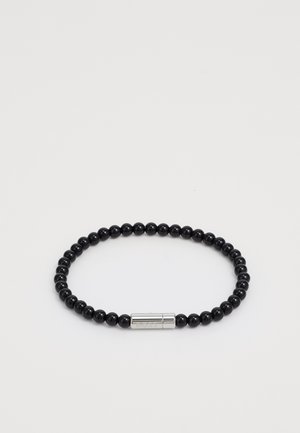 Black beaded bracelet made of glossy round stones, featuring a smooth silver clasp with engraved detailing. Simple, circular design.