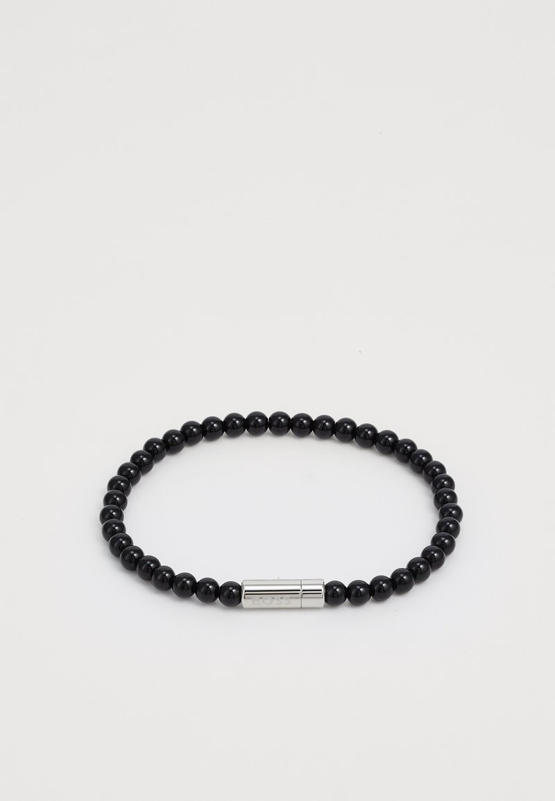 Must mustriga käevõru läikivate ümarate kivide pärlitest, millel on sile hõbedane lukk, millel on graveeritud detailid. Lihtne, ümmargune disain.