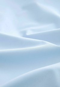Tissu bleu clair à la texture lisse et mate, présentant de douces plis et une couleur uniforme sans motifs ni matériel visible.
