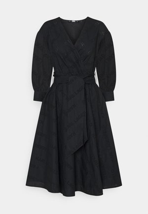 Czarna sukienka kopertowa z długimi bufkowatymi rękawami, dekoltem w serek, szerokim paskiem wiązanym w talii oraz subtelnym wzorem z perforowanego tekstu na całej powierzchni.