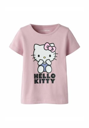 Pink kortærmet t-shirt med Hello Kitty-figur iført blå overall og lyserød sløjfe, med teksten "HELLO KITTY" under grafikken.