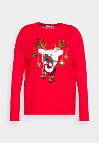 Pullover natalizio rosso brillante con un volto di renna in paillettes luccicanti e ornamenti dorati appesi alle sue corna.