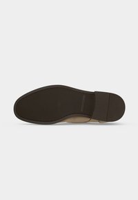 Semelle d'une chaussure de ville marron avec une semelle en caoutchouc texturée et une partie talon bien définie sur un fond clair.