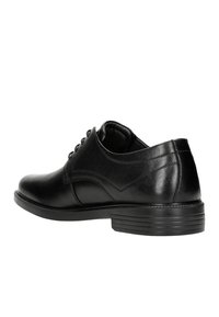 Scarpa in pelle nera con punta arrotondata, texture liscia, 6 occhielli e suola rigida. Presenta cuciture sottili e tacco basso.