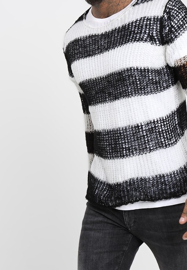 Maglione a righe bianche e nere con trama allentata, maniche corte e scollatura rotonda, abbinato a jeans scuri.