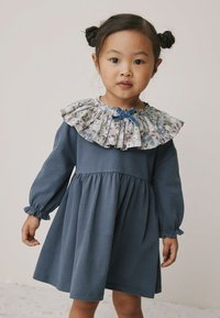 Modré šaty s dlouhými rukávy a nařaseným pasem, s květovaným volánkovým límcem a mašlí u výstřihu. Měkký bavlněný materiál.