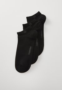 Schwarze Knöchelstrümpfe aus einem weichen Stoff, mit einem gerippten Bündchen und einem grauen "Calvin Klein"-Logo, das an der Seite aufgedruckt ist. Set aus drei Paaren.