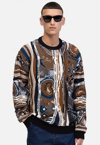 Strickpullover mit komplexen geometrischen und organischen Mustern in Braun, Blau und Weiß, ausgestattet mit einem schwarzen Rippkragen und -bündchen.