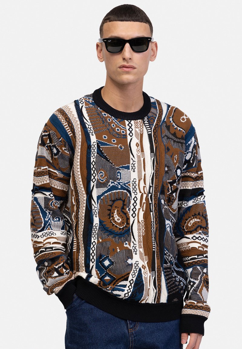 Strickpullover mit komplexen geometrischen und organischen Mustern in Braun, Blau und Weiß, ausgestattet mit einem schwarzen Rippkragen und -bündchen.