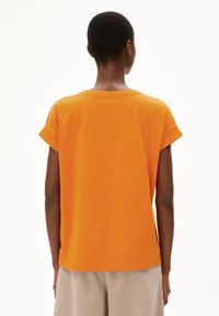 T-shirt orange à manches courtes avec encolure ronde et manches retroussées. Tissu en coton doux, coupe décontractée et ourlet droit.