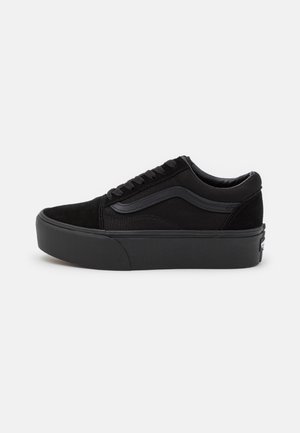 Niski czarny sneaker z grubą podeszwą, subtelnym falistym detalem i zapięciem na sznurowadła, pokazany z zewnętrznej strony na białym tle.